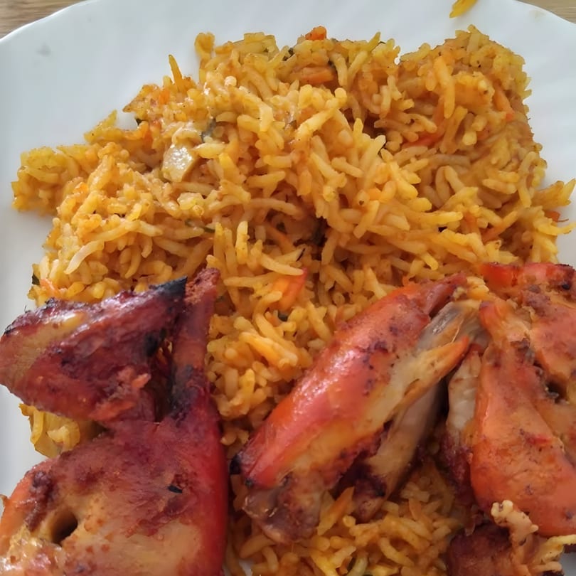 Curry Place Germantown's chicken biryani with two pieces of tandoori chicken on a white plate.